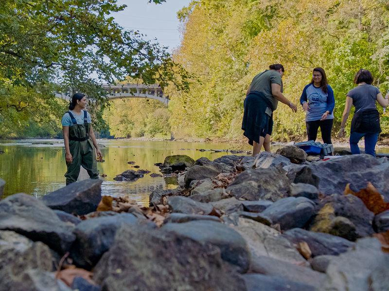 Students wearing waders clean up the Schuylkill River